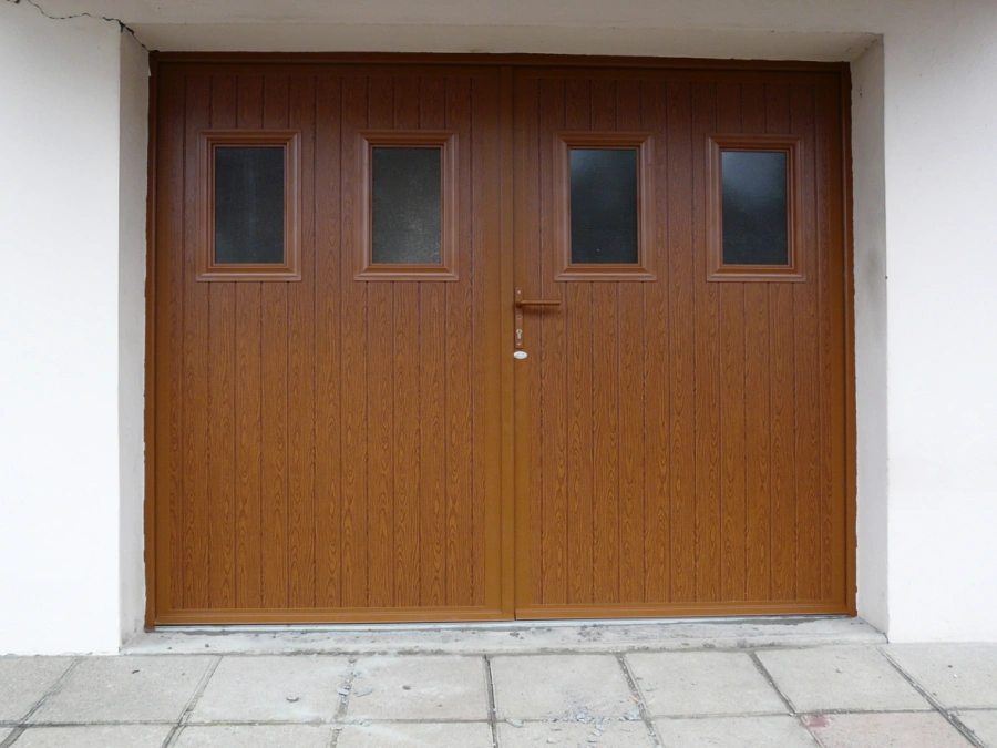 Porte de garage battante chêne doré AFC à hublots, façade crépi blanc dans le Calvados.