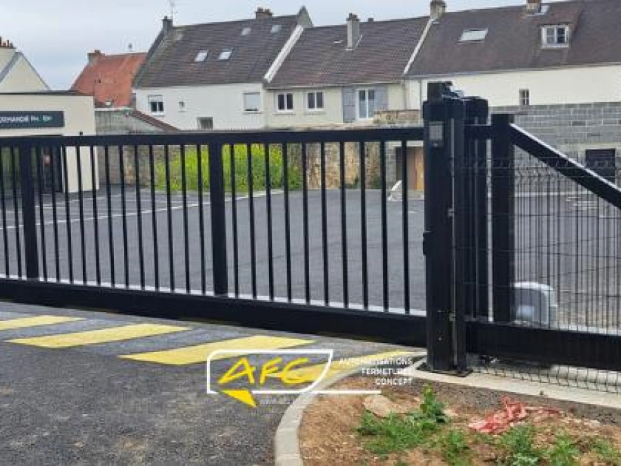Portail coulissant autoportant noir motorisé devant une pharmacie, accès parking professionnel installé par AFC à Caen.