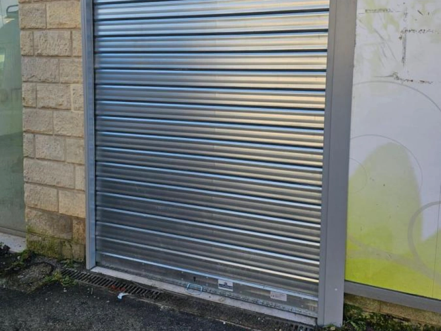 Façade de pharmacie rénovée avec rideau métallique argenté et châssis anthracite, réhabilitation AFC à Caen.