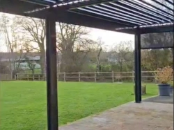 Pergola bioclimatique à lames orientables et éclairage LED intégré, store latéral, terrasse pavée AFC près de Caen.