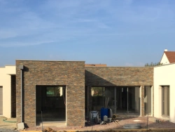 Façade contemporaine avec porte de garage grise et baies anthracite, chantier AFC dans le Calvados