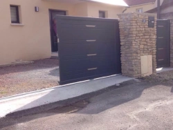Portail coulissant aluminium gris anthracite entrouvert avec portillon, entrée résidentielle dans le Calvados