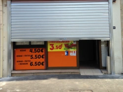 Rideau métallique argenté mi-ouvert sur vitrine de commerce, installation AFC dans le Calvados