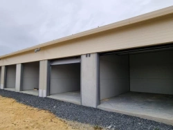 Façade de box avec portes de garage sectionnelles grises pour locaux professionnels en Normandie