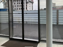 Vue intérieure d'une porte coulissante automatique vitrée cadre noir, bâtiment tertiaire Calvados